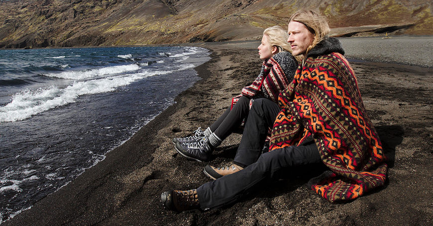 Couple wrapped in blankets on beach